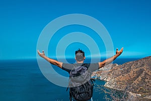 Winner / Concept of success. Hiking man cheering euphorically and happily with his arms raised in the sky after walking to the top