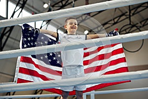 Winner emotions. Little boy, boxer with american flag on his shoulders celebrating his victory. Strength, sport, win