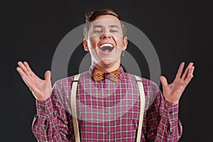 Always winner! Handsome young scientist in vintage shirt and bow tie gesturing keeping hands up and laughing while standing