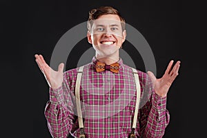 Always winner! Handsome young scientist in vintage shirt and bow tie gesturing keeping hands up and laughing while standing