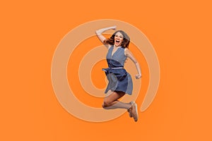 Winner joy. Full length of energetic vivid brunette woman in denim dress flying in air with inspired ecstatic expression