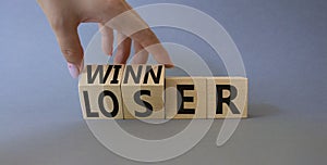 Winner and Loser symbol. Businessman hand turnes wooden cubes and changes word Looser to Winner. Beautiful grey background.