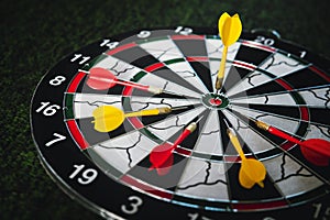 Winner yellow dart arrow hit center target of dartboard and other arrow loser metaphor marketing competition concept, on dark