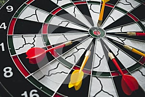 Winner yellow dart arrow hit center target of dartboard and other arrow loser metaphor marketing competition concept, on dark