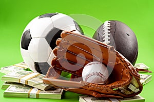 Winning bet on sporting event, money in sport and sports betting conceptual idea with baseball glove, football, soccer ball and