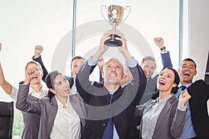 Winning business team with an executive holding trophy