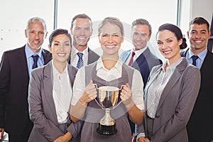 Winning business team with an executive holding trophy