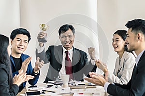 Winning business team with a man executive holding a gold trophy