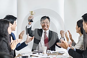 Winning business team with a man executive holding a gold trophy.