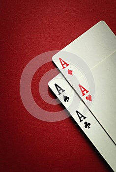 A winning combination of four aces in playing cards or four of a kind or quads. Concept of luck in the game of poker on a red