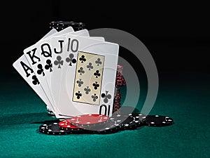 Winning combination in poker standing leaning on chips piles on green cover of playing table. Black background. Close-up