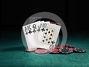 Winning combination in poker standing leaning on chips piles on green cover of playing table. Black background. Close-up