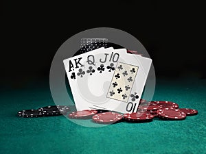 Winning combination in poker standing leaning on colored chips piles on green cover of playing table. Black background