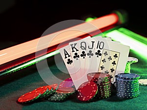 Winning combination in poker standing leaning on multicolored chips piles on green cover of playing table, under green