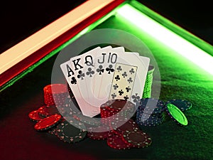 Winning combination in poker standing leaning on multicolored chips piles on green cover of playing table, under green