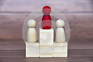 Winning concept - Red figure in the middle of other figure on wooden blocks. Conceptual