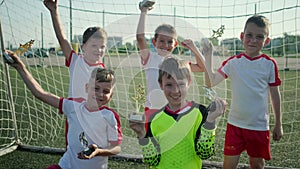 Winning football team of little boys is demonstrating rewards on stadium