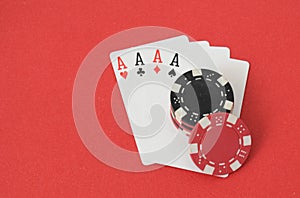 A winning hand of four aces and poker chips on a red background