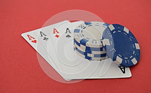 A winning hand of four aces and poker chips on a red background