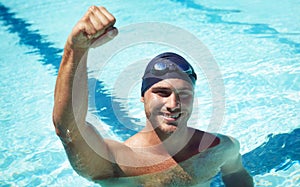 Winning. A handsome young swimmer wearing goggles and a swimming cap.