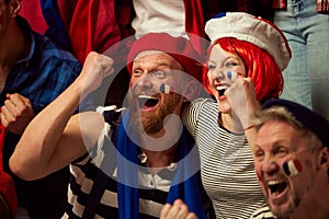 Winning match. Football, soccer fans emotionally cheering up favourite france team. People wearing country's