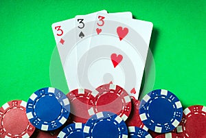 The winning poker combination is three kind or set. Chips and cards on green table in poker club