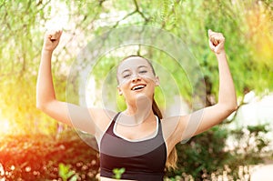 Winning, success concept. Beautiful, fitness sport girl rejoices in victory, raises her hands up.