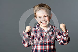 Winning young child with tooth missing raising arms for excitement