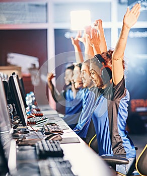 Winning. Young multiracial team of happy professional cyber sport gamers celebrating success, raising hands up while