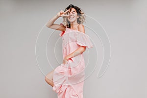 Winsome girl in pink attire posing on light background with pretty smile. Studio portrait of dancin