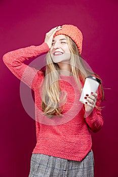 Winsome Positive Young Happy Emotional Cheerful Caucasian Girl Laughing In Knitted Autumn Hat and Sweater With Cup of Coffee on