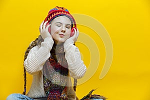 Winsome and Smiling Caucasian Blond Girl In Warm Knitted Hat and Scarf Making Faces While Listening to Music in Wireless