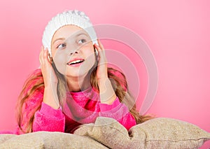 Winter accessory concept. Girl long hair dream pink background. Kid dreamy lean on pillows. Winter season coziness