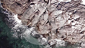 winter aerial flight top over waves rolling on artic ocean shore with round stones, ocean waves at storm