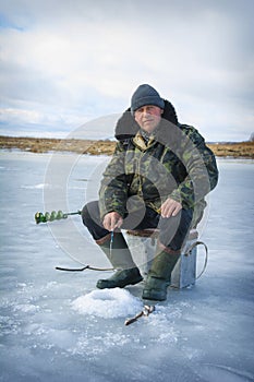 In the winter afternoon, a man sits on the river fishing, he caught a roach