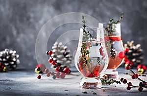 Winter alcoholic cocktail with red berries, liquor, gin, thyme and vodka for Christmas or New Year. Holiday table setting