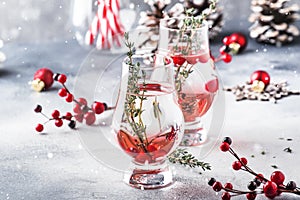 Winter alcoholic cocktail with red berries, liquor, gin, thyme and vodka for Christmas or New Year. Holiday table setting