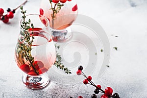 Winter alcoholic cocktail with red berries, liquor, gin, thyme and vodka for Christmas or New Year. Holiday table setting