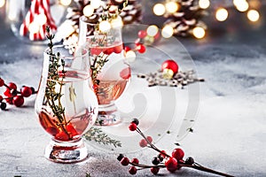 Winter alcoholic cocktail with red berries, liquor, gin, thyme and vodka for Christmas or New Year. Holiday table setting