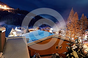 Winter Alpine village on the snowy mountain slope illuminated by street lights