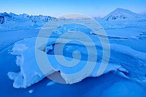 Winter Arctic. White snowy mountain, blue glacier Svalbard, Norway. Ice in ocean. Iceberg twilight in North pole. Pink clouds with