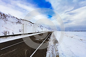 Winter asphalt road in the mountains covered with snow in overcast day. Winter landscape. The concept of freedom and