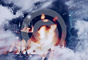 Winter atmosphere and Christmas holiday time, wine glasses in front of fireplace covered with snowy effect on window