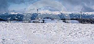 Winter austrian alps panorama with wind turbines and snow covered peaks