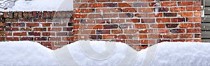 Winter background, falling snow and piles of snow on a fence railing with a brick chimney in the background