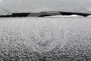 Winter background. Frozen car windshield covered with ice and snow on cold winter day. Snow covered car front window