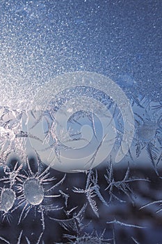 Winter background. Frozen window in winter time. Frost pattern on the window. Icy flowers on a glass