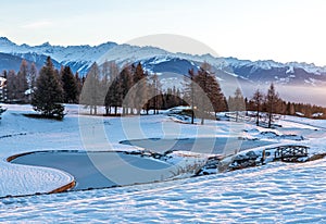 Winter background. Snow, icy water, trees and mountain in Crans Montana in Switzerland. Tranquil scene photo