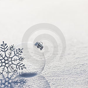 Winter background with transparent glass ball and silver snowflakes on whiteness snow surface. Merry Christmas and Happy New year