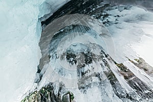 Winter Baikal. Olkhon Island. Ice grotto. Thick blue ice and icicles on the coastal rocks of Olkhon Island in winter